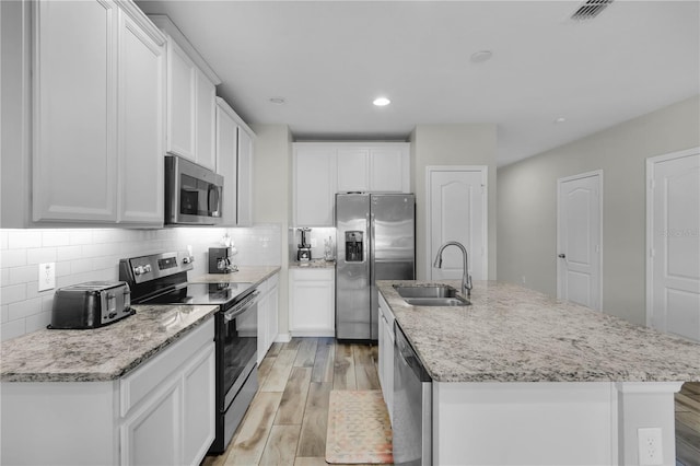 kitchen with a center island with sink, white cabinets, sink, and stainless steel appliances