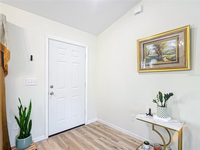 foyer entrance with light hardwood / wood-style flooring and vaulted ceiling