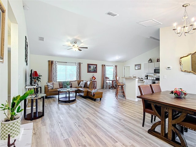 living room featuring lofted ceiling, light wood-type flooring, and ceiling fan with notable chandelier