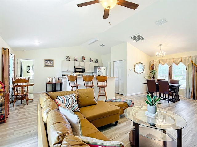 living room featuring ceiling fan with notable chandelier, light hardwood / wood-style floors, and vaulted ceiling