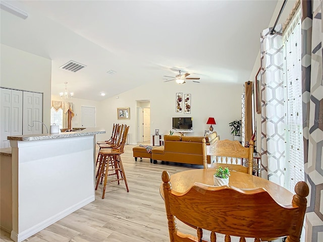 dining room with light wood-type flooring, lofted ceiling, and ceiling fan with notable chandelier