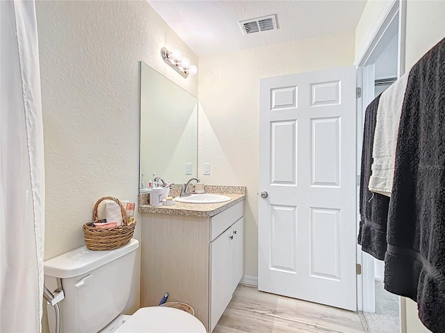 bathroom with wood-type flooring, vanity, and toilet