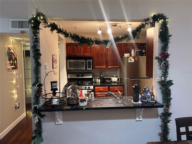 kitchen featuring kitchen peninsula, dark hardwood / wood-style floors, a kitchen bar, appliances with stainless steel finishes, and sink