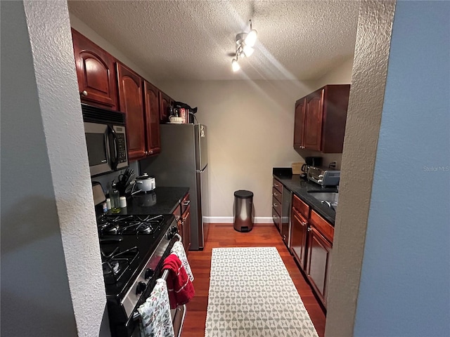 kitchen featuring a textured ceiling, track lighting, black appliances, and hardwood / wood-style floors