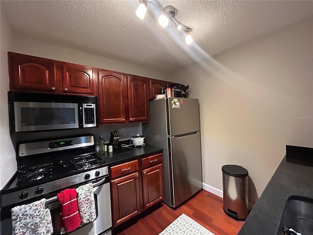 kitchen with stainless steel appliances, a textured ceiling, and dark hardwood / wood-style floors