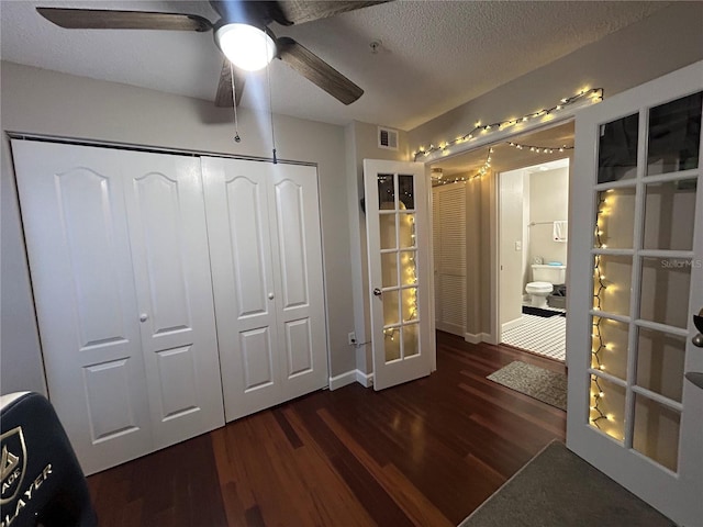 unfurnished bedroom featuring a textured ceiling, french doors, ceiling fan, a closet, and dark wood-type flooring