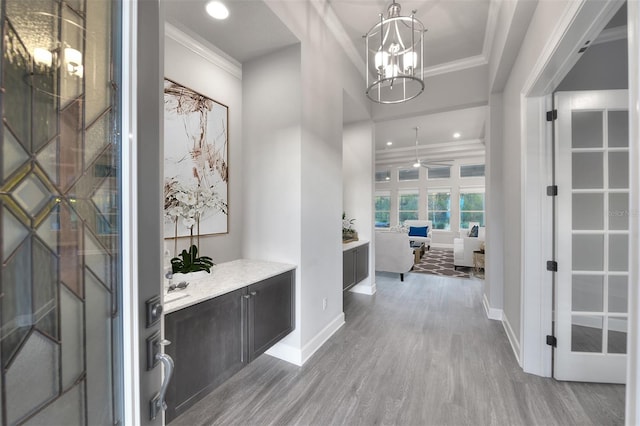 corridor with a chandelier, hardwood / wood-style floors, and ornamental molding