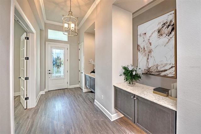 foyer entrance featuring a notable chandelier, dark hardwood / wood-style flooring, and ornamental molding