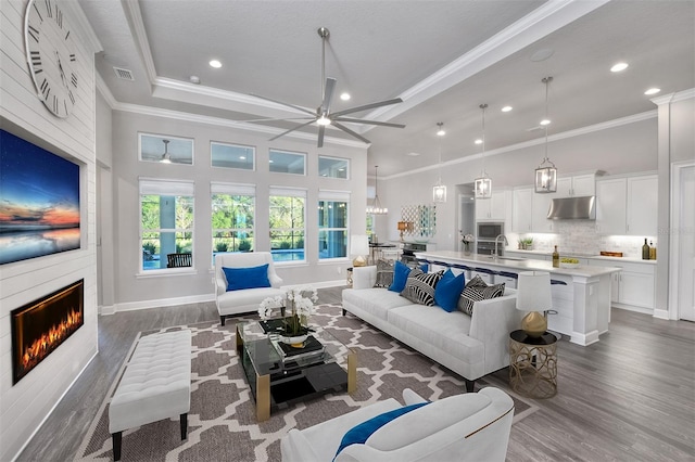 living room featuring a large fireplace, ceiling fan, sink, and dark wood-type flooring