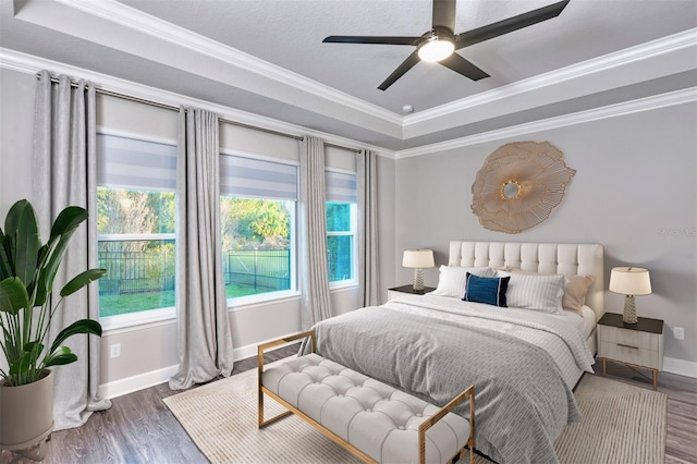 bedroom with ceiling fan, dark hardwood / wood-style floors, crown molding, and a tray ceiling