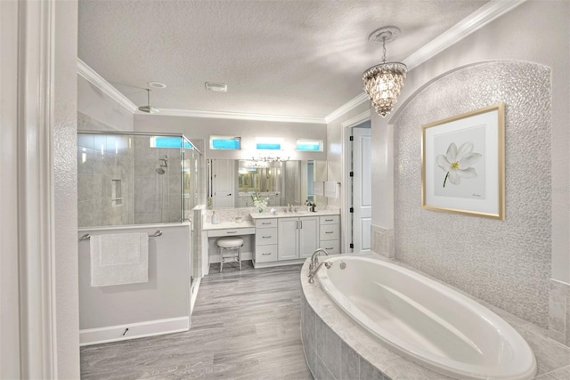 bathroom with an inviting chandelier, crown molding, shower with separate bathtub, vanity, and hardwood / wood-style flooring