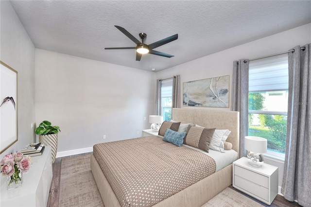 bedroom with ceiling fan, a textured ceiling, and hardwood / wood-style flooring