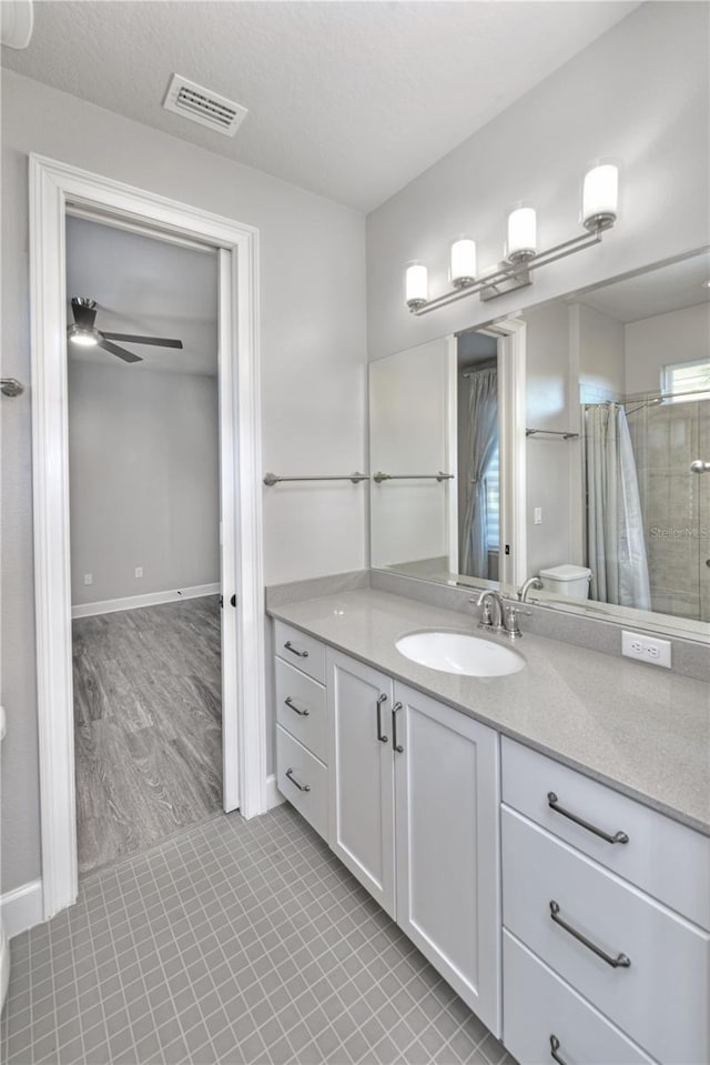 bathroom with tile patterned floors, vanity, ceiling fan, toilet, and curtained shower