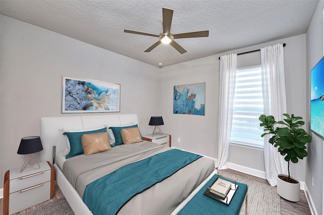 bedroom featuring multiple windows, ceiling fan, a textured ceiling, and hardwood / wood-style flooring