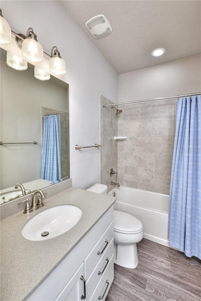 full bathroom featuring vanity, shower / bath combination with curtain, hardwood / wood-style flooring, toilet, and a textured ceiling