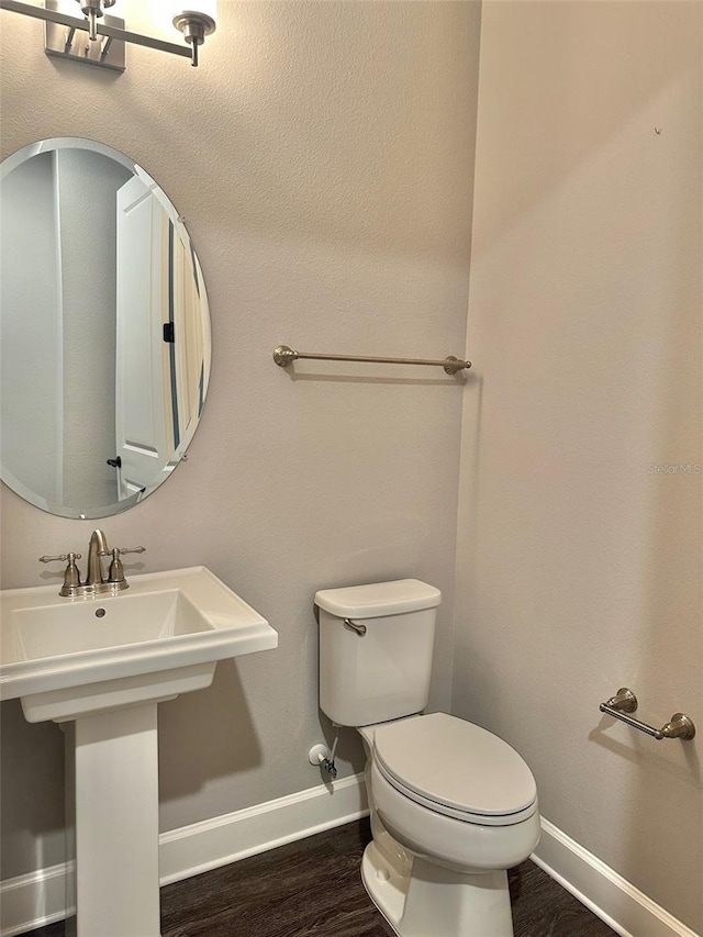 bathroom featuring wood-type flooring, toilet, and sink