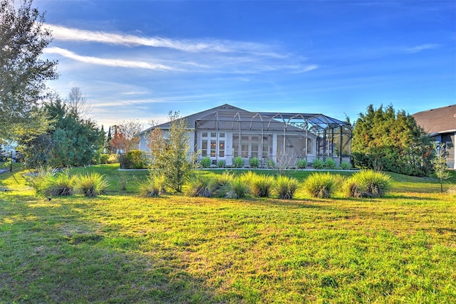 rear view of property with a lawn and a lanai