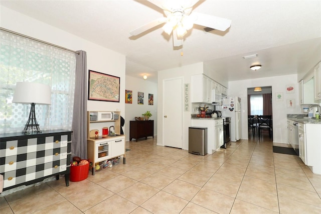 kitchen with white cabinets, ceiling fan, light tile patterned flooring, and sink