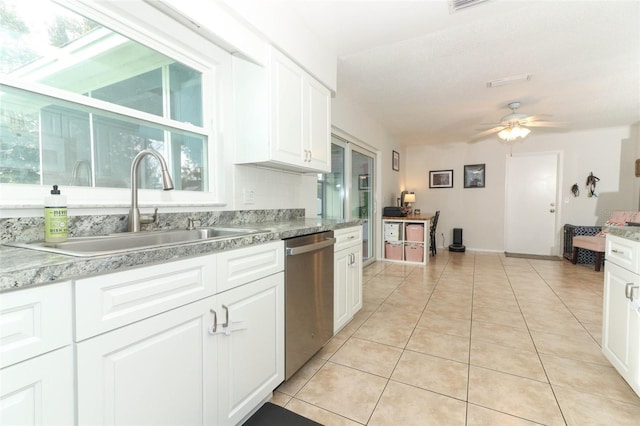 kitchen with sink, stainless steel dishwasher, ceiling fan, light tile patterned flooring, and white cabinetry