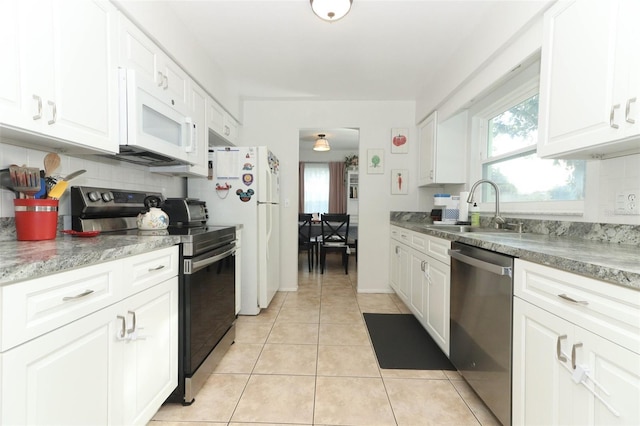 kitchen with white appliances, sink, light tile patterned floors, tasteful backsplash, and white cabinetry