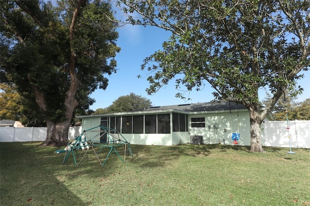 rear view of house with a yard, cooling unit, and a sunroom