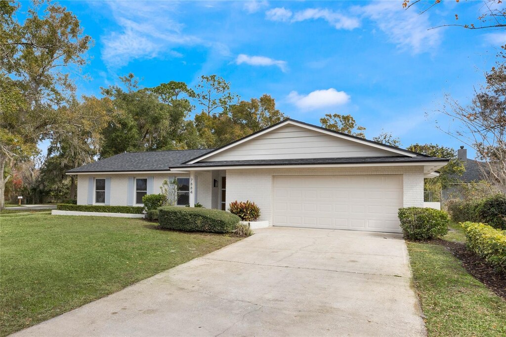 ranch-style home featuring a garage, a front yard, concrete driveway, and brick siding