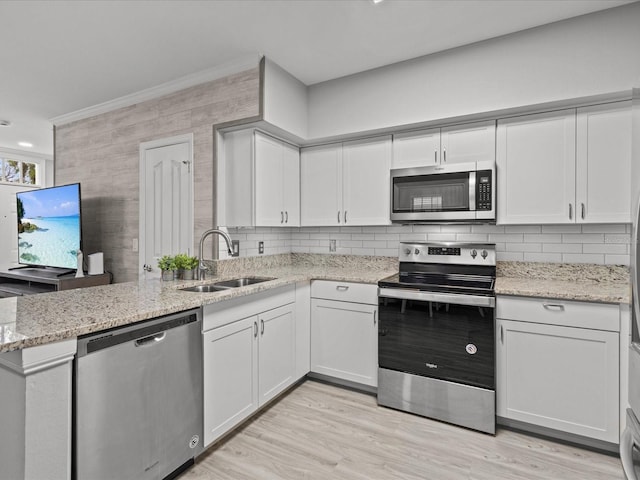 kitchen featuring white cabinets, stainless steel appliances, decorative backsplash, sink, and light hardwood / wood-style flooring