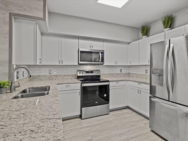 kitchen featuring white cabinets, stainless steel appliances, tasteful backsplash, and sink