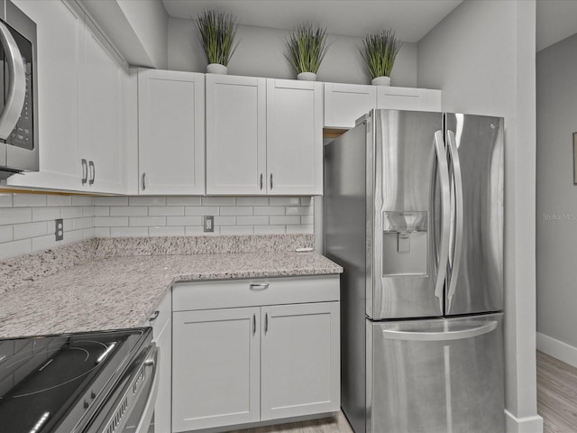 kitchen with light stone counters, white cabinets, backsplash, and appliances with stainless steel finishes