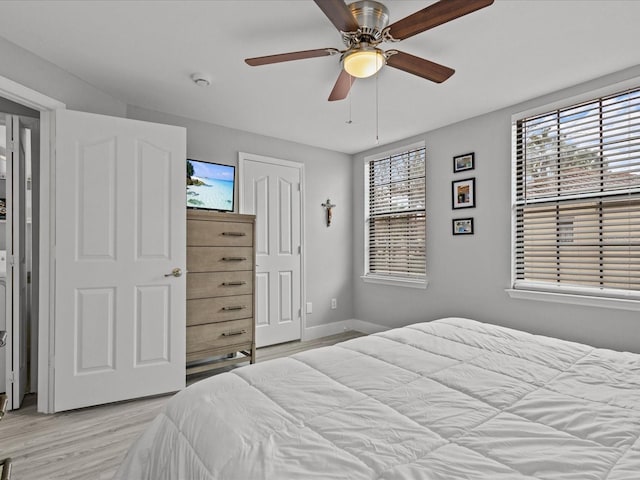 bedroom with multiple windows, light hardwood / wood-style flooring, and ceiling fan