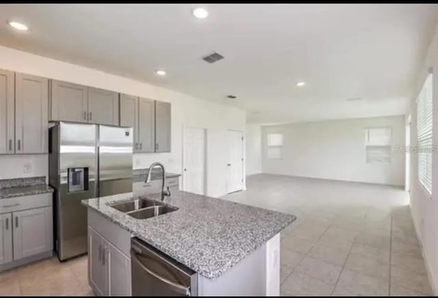 kitchen featuring gray cabinetry, sink, stainless steel appliances, and a center island with sink