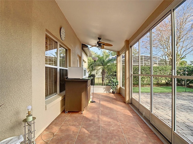 unfurnished sunroom featuring ceiling fan and a healthy amount of sunlight