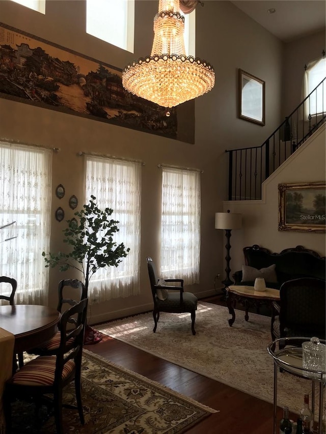 dining space featuring a high ceiling, dark hardwood / wood-style floors, plenty of natural light, and a notable chandelier