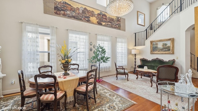 dining space with a high ceiling, wood-type flooring, and a notable chandelier