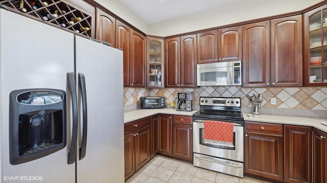 kitchen with backsplash, stainless steel appliances, and light tile patterned floors