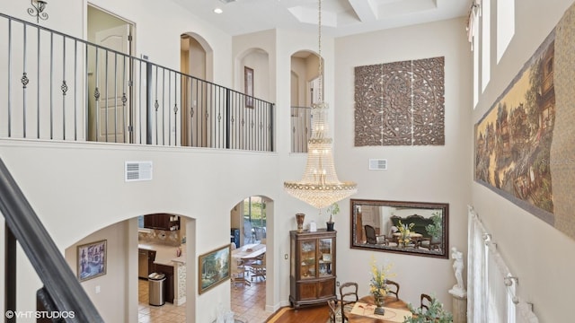 stairs with tile patterned floors, coffered ceiling, and a high ceiling