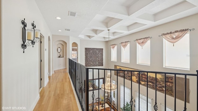 hallway with coffered ceiling, beam ceiling, and light hardwood / wood-style flooring