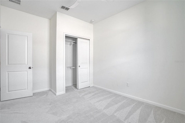 unfurnished bedroom featuring light colored carpet and a closet