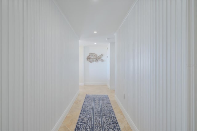 corridor featuring light tile patterned flooring, crown molding, and wood walls