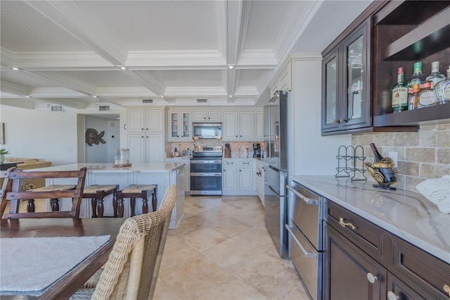 kitchen with tasteful backsplash, dark brown cabinetry, stainless steel appliances, and beam ceiling