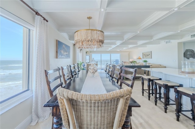 carpeted dining area with coffered ceiling, crown molding, beam ceiling, a water view, and an inviting chandelier