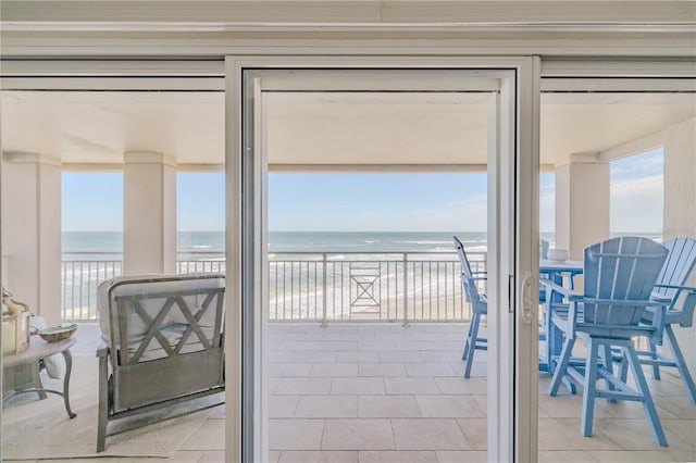 interior space featuring light tile patterned floors, a water view, and a view of the beach