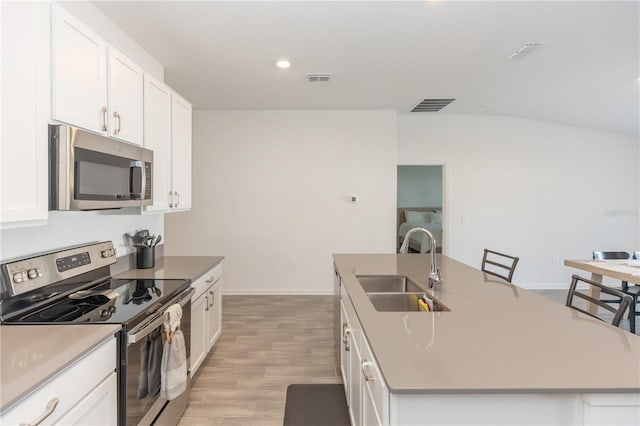 kitchen featuring stainless steel appliances, white cabinetry, a center island with sink, and sink