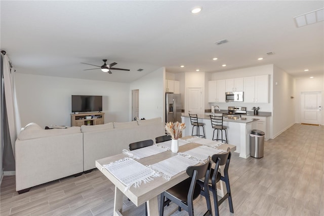 dining area with ceiling fan, sink, and light hardwood / wood-style floors