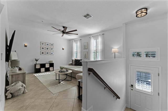 living room featuring light tile patterned floors, a textured ceiling, and ceiling fan