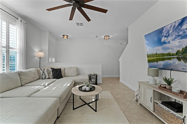 living room featuring ceiling fan, light tile patterned flooring, and a textured ceiling