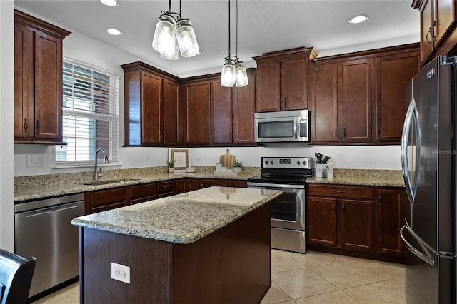 kitchen with sink, a center island, decorative light fixtures, light tile patterned floors, and appliances with stainless steel finishes