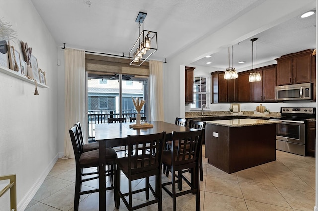 kitchen featuring pendant lighting, a center island, sink, dark brown cabinetry, and stainless steel appliances