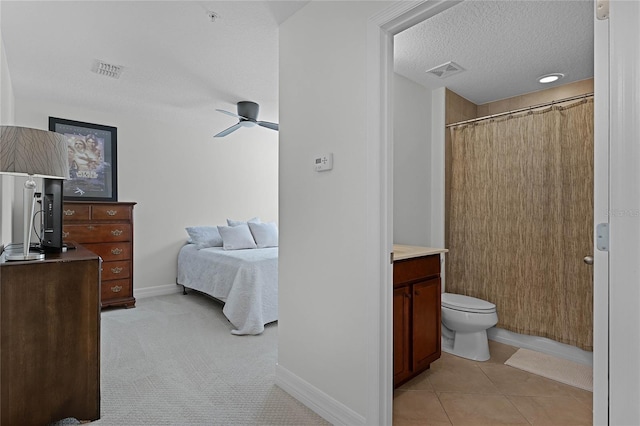 bathroom with tile patterned floors, vanity, a textured ceiling, ceiling fan, and toilet