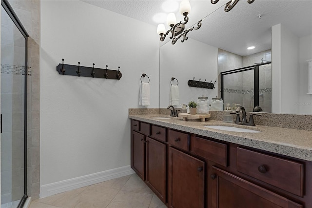 bathroom with tile patterned flooring, vanity, a shower with shower door, and a textured ceiling